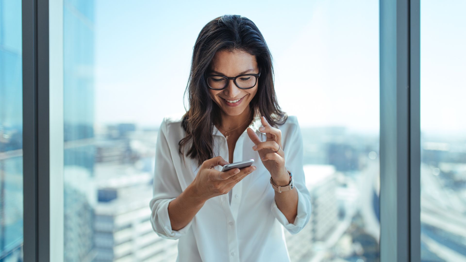 girl in front of a window looking at a phone